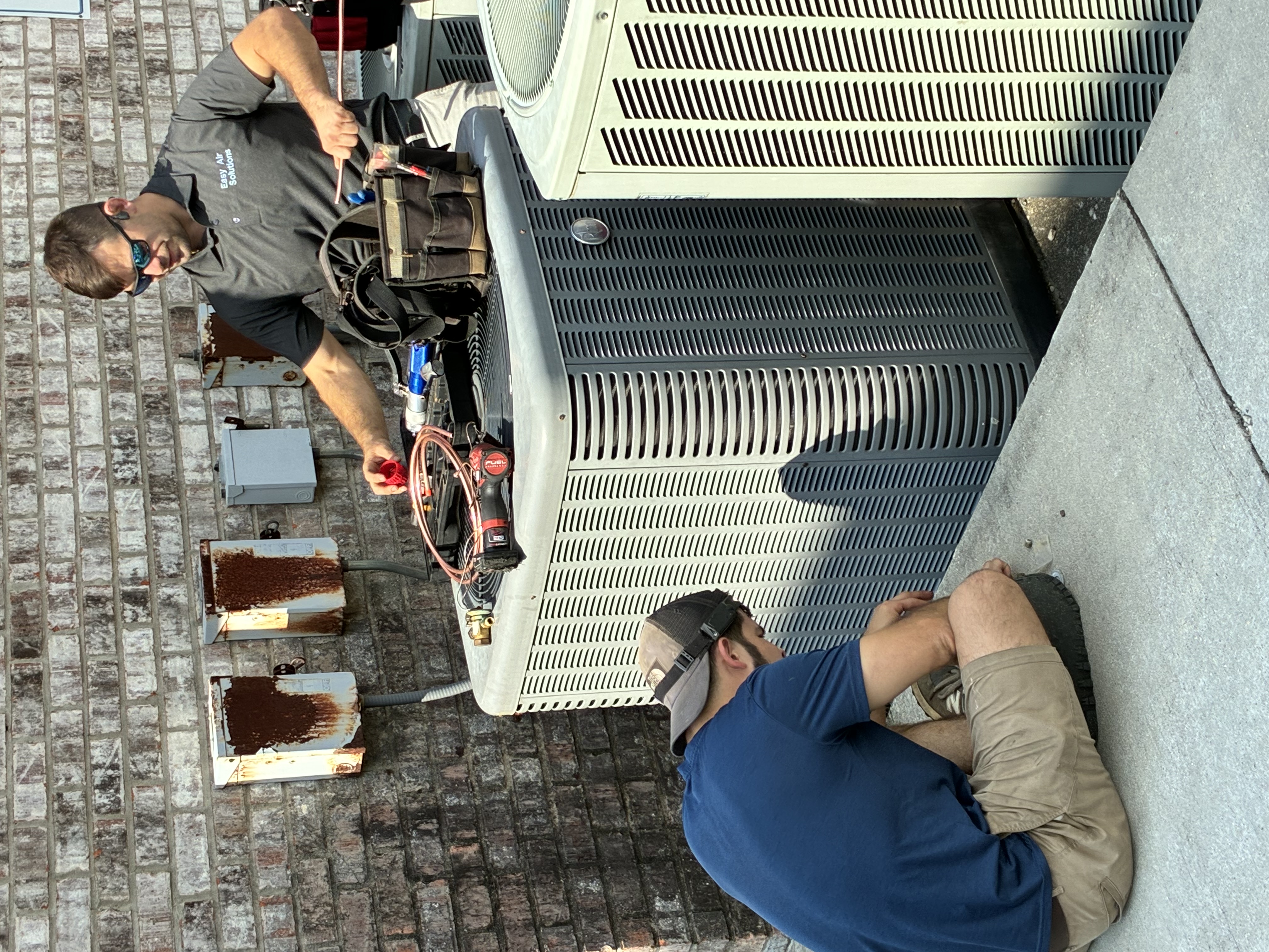 Easy Air Solutions technicians servicing an outdoor AC condenser unit